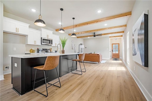 kitchen featuring stainless steel appliances, white cabinets, ceiling fan, pendant lighting, and beam ceiling