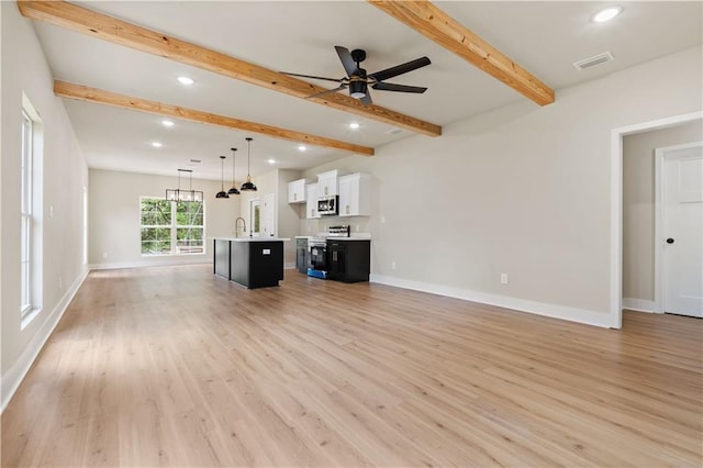 unfurnished living room with ceiling fan, light hardwood / wood-style flooring, sink, and beamed ceiling