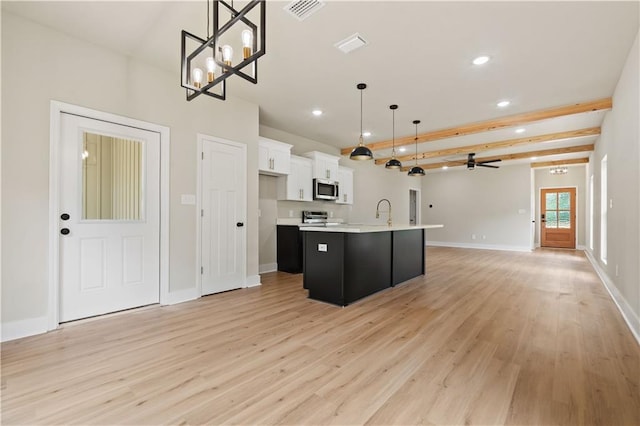 kitchen with hanging light fixtures, stainless steel appliances, an island with sink, white cabinets, and ceiling fan