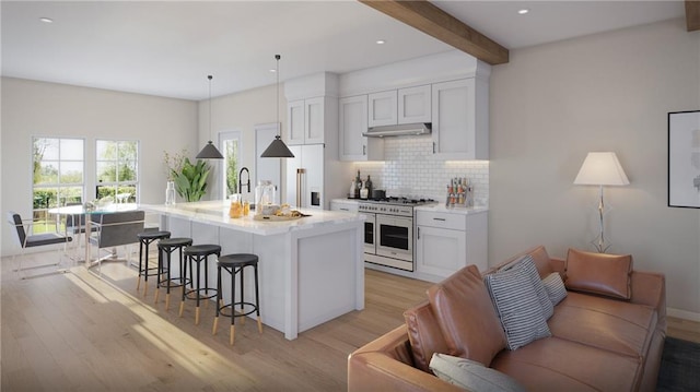 kitchen featuring white cabinetry, beamed ceiling, high end appliances, hanging light fixtures, and a kitchen island with sink