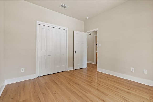 unfurnished bedroom with light wood-type flooring and a closet