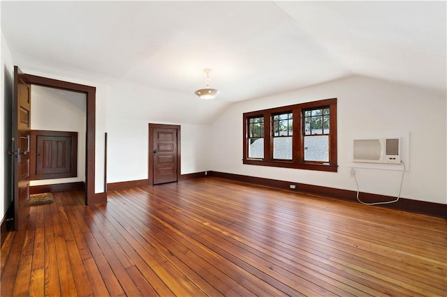 additional living space with lofted ceiling, dark wood-type flooring, and a wall mounted air conditioner