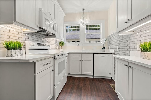 kitchen featuring sink, white cabinetry, hanging light fixtures, dark hardwood / wood-style floors, and white appliances