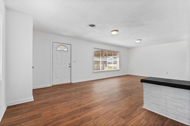 unfurnished living room featuring visible vents, baseboards, and wood finished floors