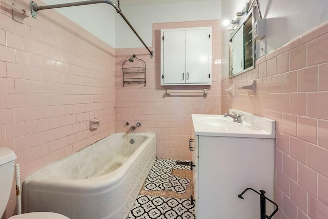 bathroom with tile patterned floors, toilet, vanity, shower / bathing tub combination, and tile walls