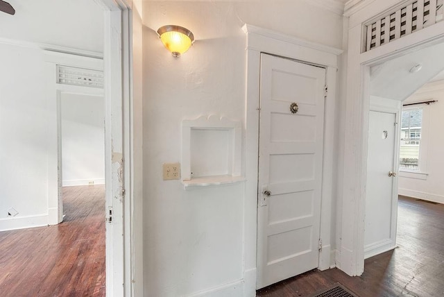 corridor with visible vents, baseboards, and dark wood finished floors