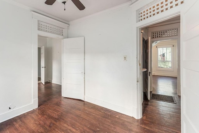 empty room featuring a ceiling fan, ornamental molding, baseboards, and wood finished floors