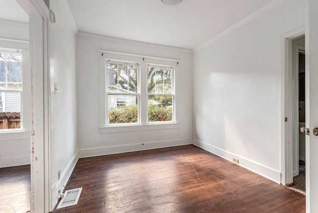 unfurnished room featuring hardwood / wood-style floors, ornamental molding, baseboards, and visible vents