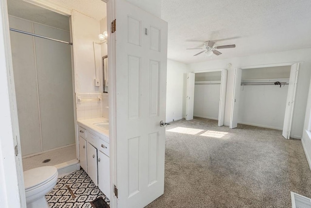 bathroom featuring toilet, vanity, a ceiling fan, a textured ceiling, and visible vents