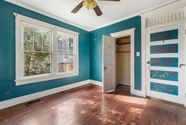 unfurnished bedroom featuring ornamental molding, baseboards, visible vents, ceiling fan, and wood finished floors