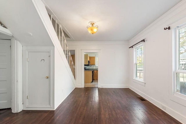 spare room with plenty of natural light, crown molding, stairway, and wood finished floors