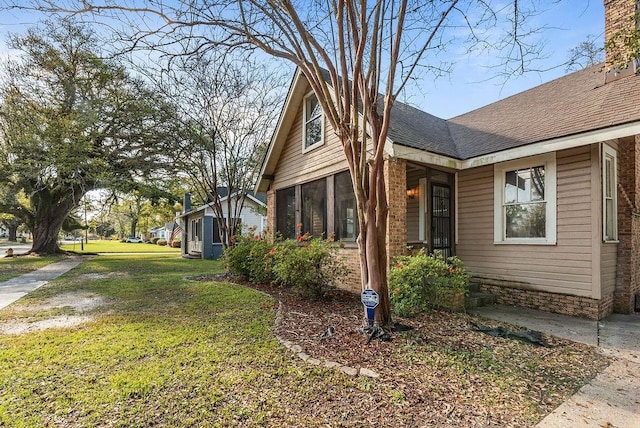 view of property exterior featuring a shingled roof and a yard