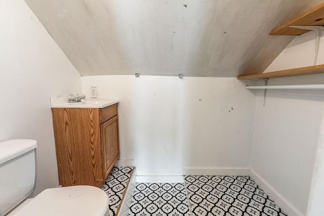 bathroom with baseboards, toilet, vaulted ceiling, and vanity