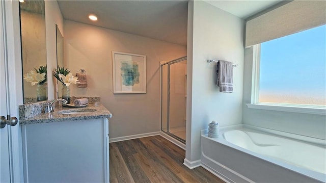 full bath with baseboards, wood finished floors, a garden tub, vanity, and a shower stall