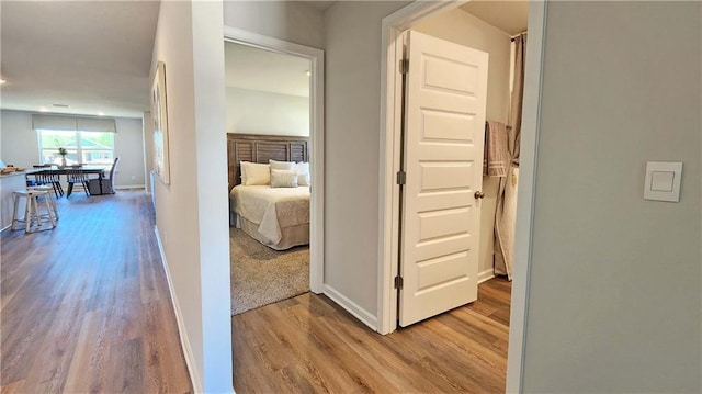 corridor featuring light wood-style flooring and baseboards