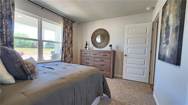 bedroom with light carpet, a textured ceiling, and baseboards