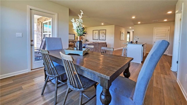 dining space featuring baseboards, wood finished floors, and recessed lighting