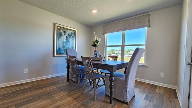 dining space with dark wood finished floors, a textured ceiling, and baseboards