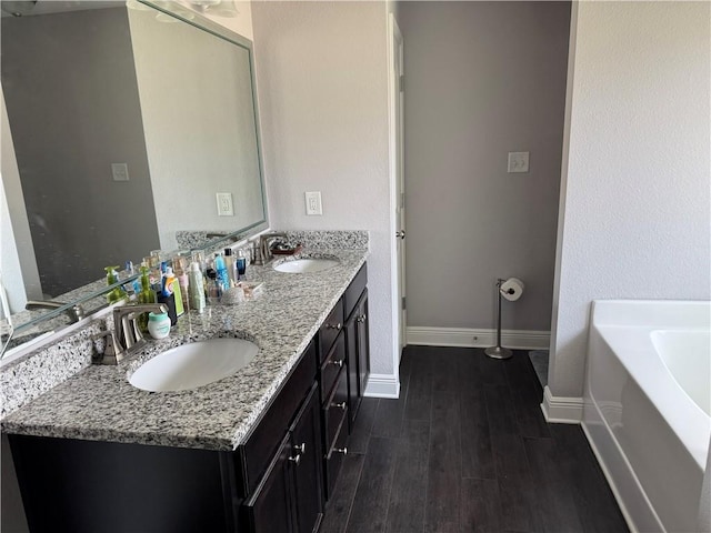 bathroom with double vanity, a sink, a bath, and wood finished floors