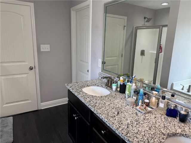 bathroom featuring a stall shower, wood finished floors, vanity, and baseboards