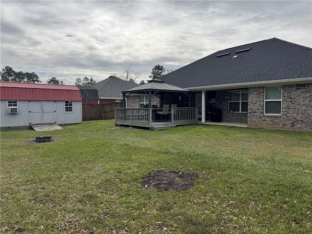 back of house featuring a lawn, a gazebo, a wooden deck, a shed, and an outdoor structure