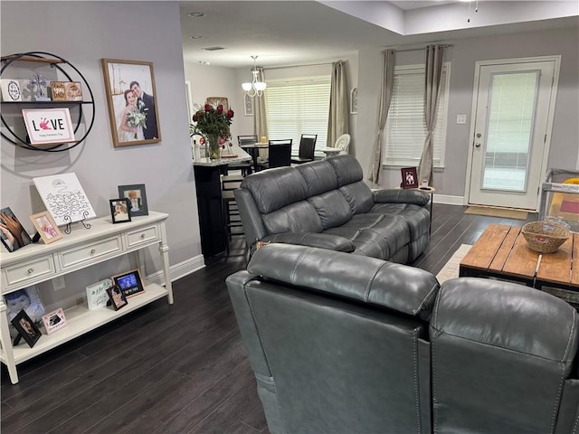 living room featuring a notable chandelier, baseboards, and dark wood-type flooring