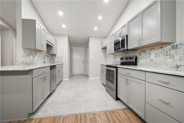 647 Spring Lake Ct, Mobile, AL 36695 - kitchen featuring appliances with stainless steel finishes, gray cabinetry, vaulted ceiling, tasteful backsplash, and light stone counters