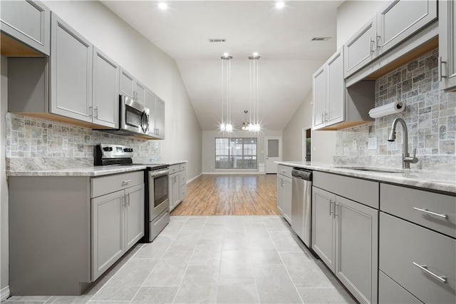 647 Spring Lake Ct, Mobile, AL 36695 - kitchen featuring appliances with stainless steel finishes, gray cabinets, vaulted ceiling, light stone counters, and backsplash