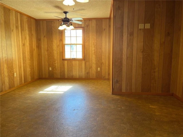 empty room with ceiling fan, ornamental molding, a textured ceiling, and wood walls