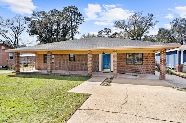 single story home with driveway, brick siding, roof with shingles, and a front yard