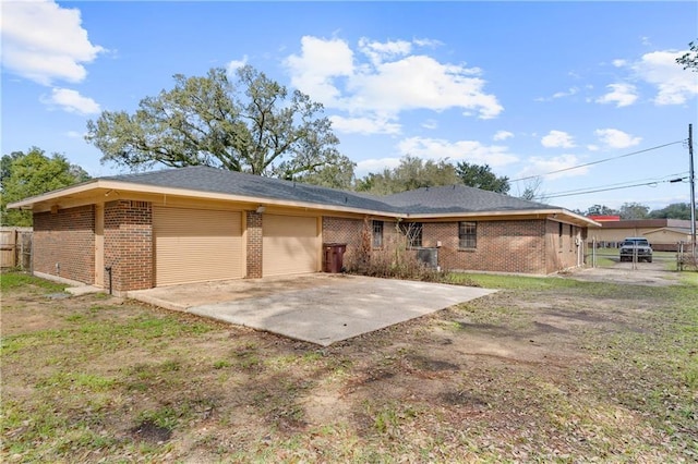 view of front of house featuring a garage, concrete driveway, brick siding, and fence