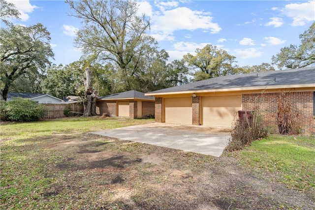 view of front of property with a garage, brick siding, fence, and a front lawn