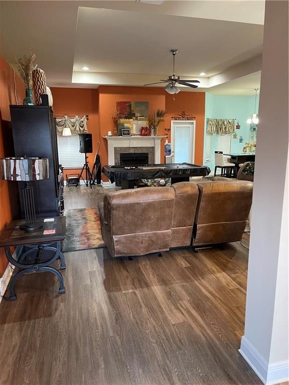 living room with wood-type flooring, a raised ceiling, and ceiling fan