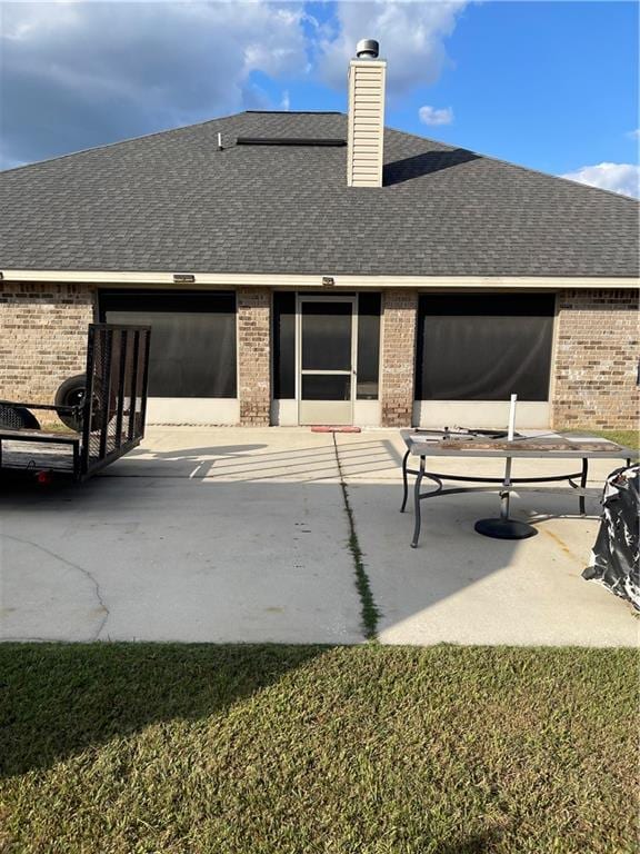 rear view of house with a patio and a lawn