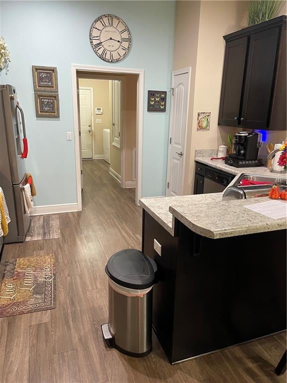 kitchen featuring kitchen peninsula, stainless steel fridge, hardwood / wood-style flooring, and sink