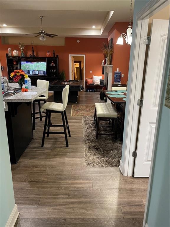 dining area featuring a tray ceiling, wood-type flooring, and ceiling fan with notable chandelier