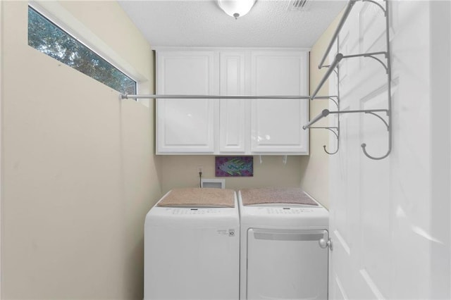 laundry area featuring cabinets, a textured ceiling, and washer and clothes dryer