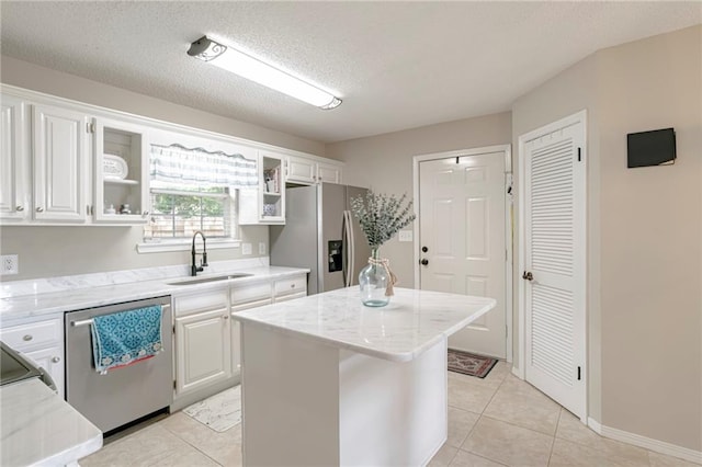 kitchen featuring appliances with stainless steel finishes, white cabinetry, a kitchen island, a textured ceiling, and sink