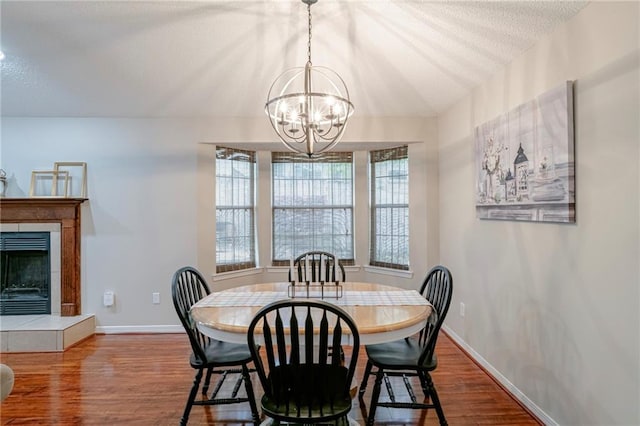 dining room with a textured ceiling, a fireplace, a chandelier, and hardwood / wood-style floors