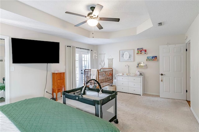 carpeted bedroom featuring ceiling fan, a textured ceiling, and a raised ceiling