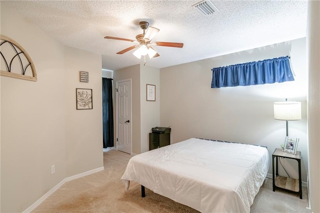 carpeted bedroom featuring ceiling fan and a textured ceiling