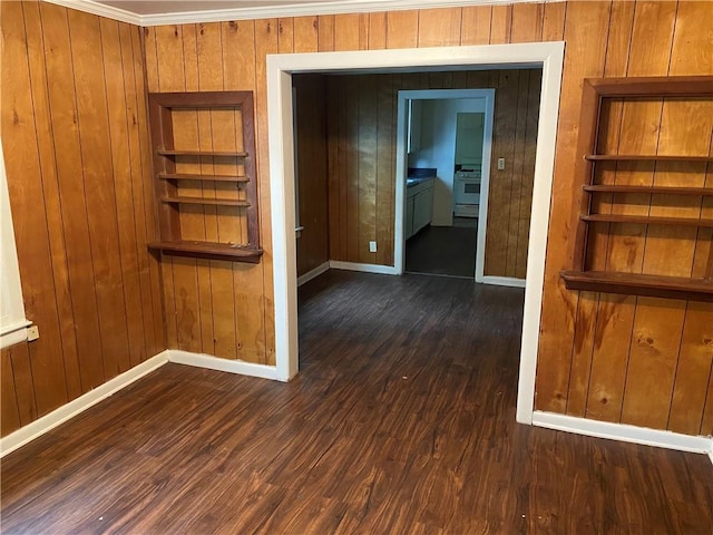 spare room featuring wood walls, baseboards, and wood finished floors