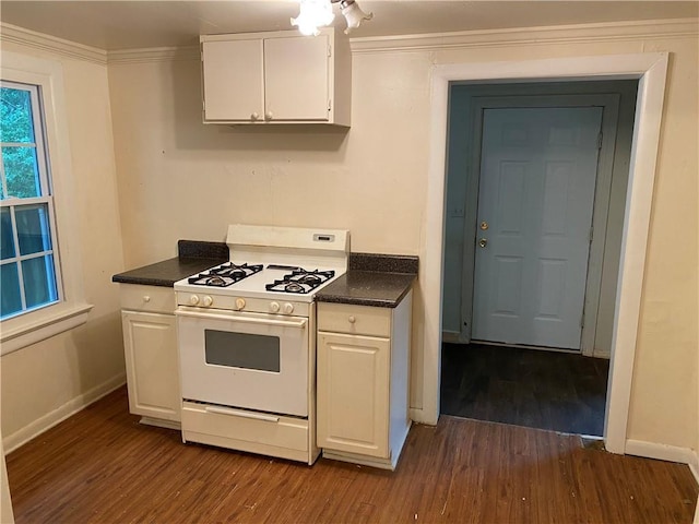 kitchen featuring ornamental molding, dark countertops, white cabinetry, and white gas stove