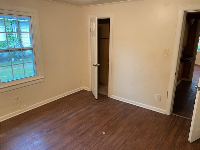 unfurnished bedroom with dark wood-style floors, a closet, and baseboards