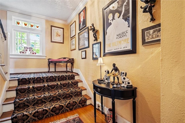 stairs featuring a textured ceiling, crown molding, and hardwood / wood-style floors