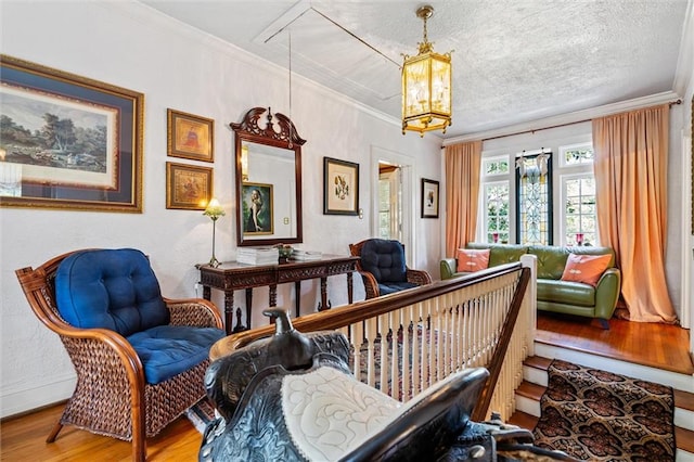 sitting room with a notable chandelier, wood-type flooring, ornamental molding, and a textured ceiling