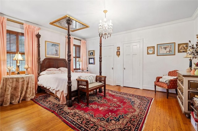 bedroom featuring light wood-type flooring, multiple closets, an inviting chandelier, and ornamental molding