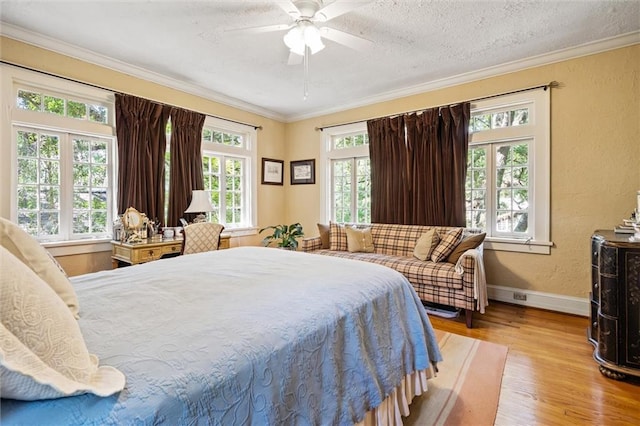 bedroom with ceiling fan, light hardwood / wood-style floors, a textured ceiling, and crown molding