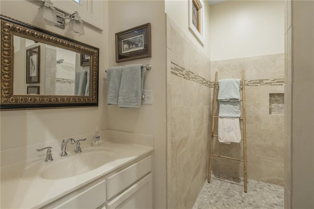 bathroom featuring tiled shower and vanity