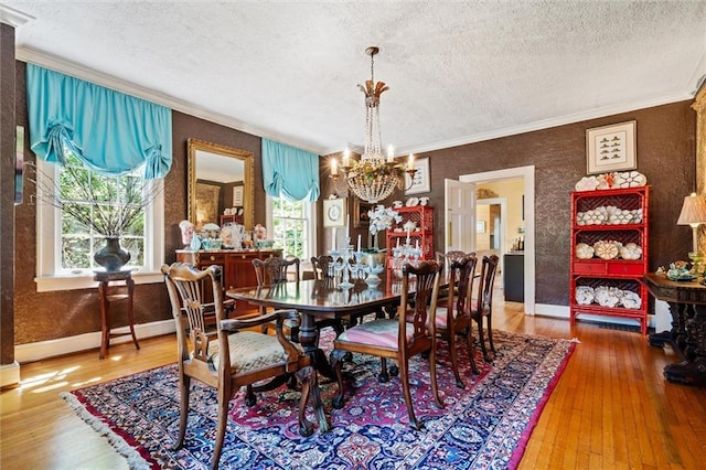 dining space featuring hardwood / wood-style floors, an inviting chandelier, ornamental molding, and a textured ceiling